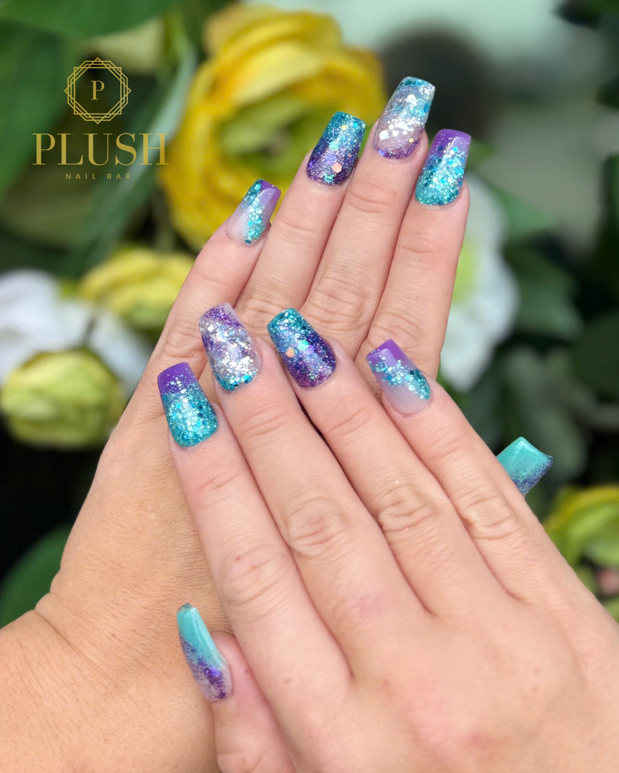 Top 5 Summer Nail Designs You Need to Try in 2025 4 Sparkly galaxy glitter nail design in purple and teal – a trendy short gel manicure for summer 2025 at Plush Nail Bar, featuring vegan gel nail polish and bold nail art ideas.