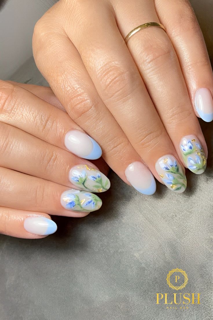 Almond-shaped nails with pastel floral designs, featuring hand-painted blue flowers and green leaves over a soft gradient base.